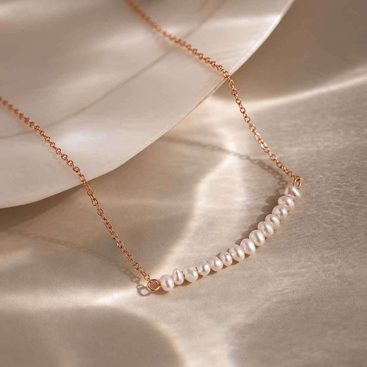 Pearl necklace with rose gold chain on a beige fabric background